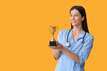 Female doctor with gold cup on yellow background