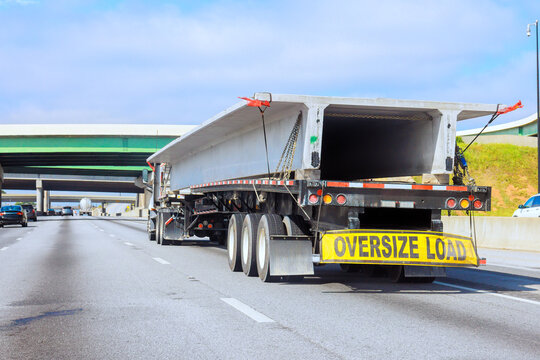 Large truck carrying oversize load concrete slabs on highway by overpasses