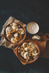 Top view of traditional dumplings served with fried onions and meat in rustic ceramic bowls, placed on burlap and a wooden board
