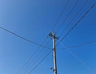Power pole and electrical wires against a brilliant blue sky. Essential utility infrastructure