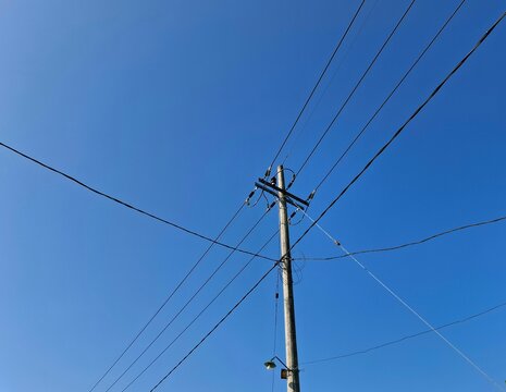 Power pole and electrical wires against a brilliant blue sky. Essential utility infrastructure