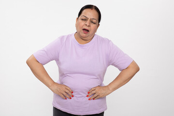 Portrait of an indian unhealthy senior woman holding her stomach pain, abdominal pain, eating...