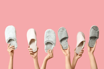 Female hands holding different women's slippers on pink background