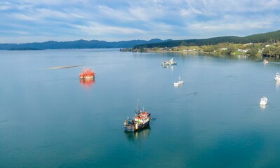 Fishing boats navigate the calm waters of the Kawhia, Waikato, New Zealand. The vessels are likely headed out to sea for the day's catch. ,
