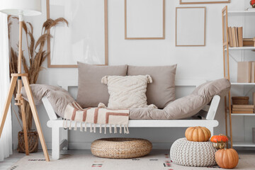 Interior of light living room with autumn decor, sofa and blank frames