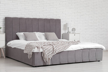 Interior of comfortable bedroom with bed, lamp, pillows and bedside tables