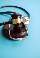 A wooden gavel and stethoscope rest on a blue background, symbolizing the intersection of law and medicine.