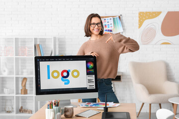 Young female graphic designer pointing at computer with stylish logo in office