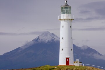Cape Egmont Lighthouse stands tall on the coast of Pungarehu, Taranaki, New Zealand, guiding ships safely. The iconic landmark is set against the backdrop of Mount Taranaki.