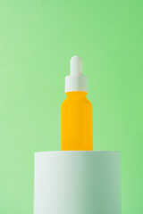 Plastic yellow tube for cream or lotion. Skin care or sunscreen cosmetic with stylish props on green background.