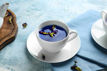 Cup of butterfly pea flower tea on blue grunge background