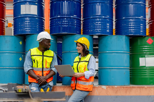 male engineer supervisor discuss progress production plan with technician oil barrel background use computer laptop, team of diverse workers working together at industrial manufacturing factory