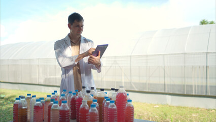 A researcher in a lab coat uses a tablet to inspect colorful liquid samples