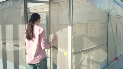 Young people examining plants in a greenhouse, learning about sustainable farming