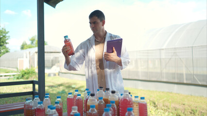 A researcher in a lab coat uses a tablet to inspect colorful liquid samples
