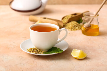 Cup of hot buckwheat tea with lemon slice and mint leaves on beige grunge background
