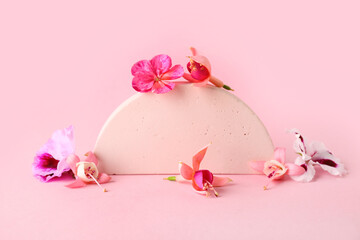 Decorative podium with different beautiful edible flowers on pink background