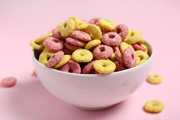 Bowl with tasty cereal rings on pink background, closeup