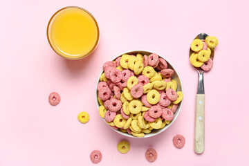 Bowl of tasty color cereal rings and glass of juice on pink background