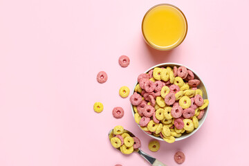 Bowl of tasty color cereal rings and glass of juice on pink background