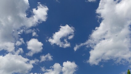 Fototapeta premium Bright blue sky filled with scattered cumulus clouds on a sunny day. A peaceful natural scene perfect for backgrounds, weather concepts, or calming visuals