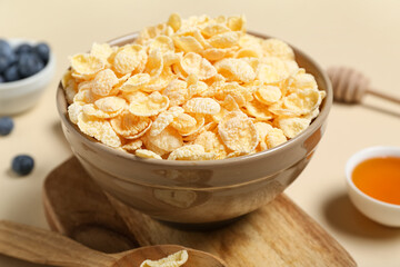 Composition with bowl of tasty cornflakes and cutting board on beige background, closeup