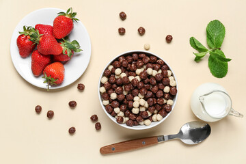 Plate with strawberry and bowl with chocolate corn balls on beige background