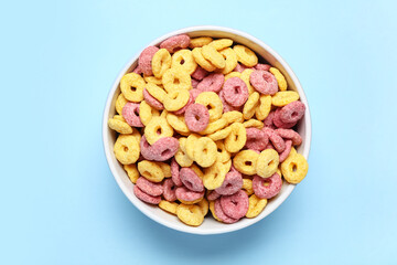 Bowl with color cereal rings on blue background, closeup