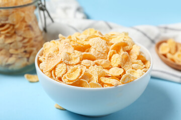 Bowl of tasty cornflakes on blue background, closeup