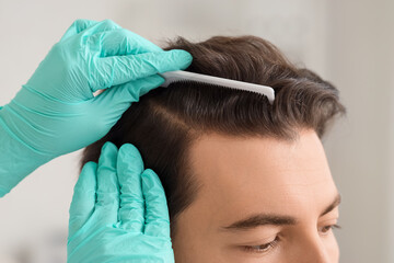 Doctor examining man in clinic, closeup. Hair loss problem