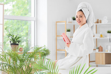 Pretty young Asian woman with shampoo in bathroom