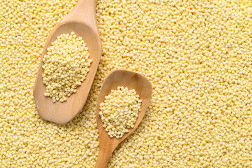 Yellow millet grain background with wooden spoon, Food ingredient, Top view