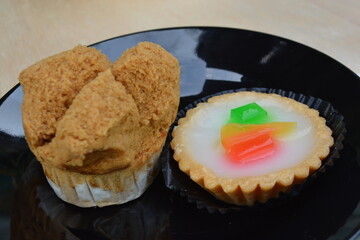 A close-up shot of a single, beautifully risen huat kueh (steamed cake) and mini tart with a golden-brown, fluted pastry shell