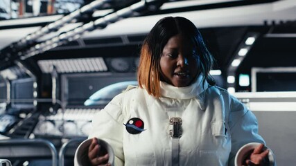 Happy female astronaut saluting command center researchers during videocall, sharing recent discoveries. African american woman in spaceship provides scientific findings to Earth team, camera B - Powered by Adobe