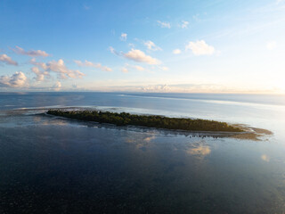 A serene sunrise silhouettes an island within Wakatobi National Park, off the coast of Sulawesi. This area is a popular destination for divers and snorkelers due to its high marine biodiversity.