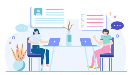 Two women sit at a table with laptops and talk. Suitable for workplace, business, networking, teamwork, diversity, and communication concepts.