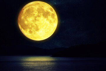 Sturgeon Super moon rising over the horizon of a calm lake at dusk.