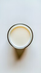 A close-up view of a glass of milk on a light background.