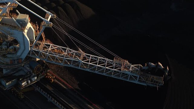 Silhouetted coal excavator in dramatic light during sunrise at Australian industrial site, high angle overview