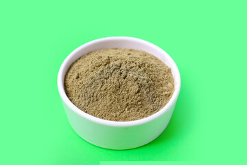 Gotu kola powder (Centella asiatica) in a white bowl on green background.