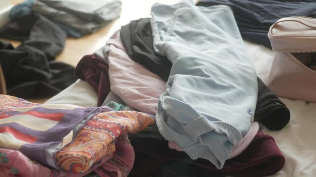Organizing clothes on a bed to declutter bedroom space