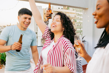 At gathering on a sunset terrace, young Latin friends celebrate with drinks