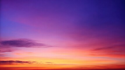 Obraz premium Breathtaking sunrise or sunset sky with deep purples, blues, and soft pink hues blending into a warm golden-orange horizon. Wispy clouds add texture and depth, creating a serene and tranquil atmospher