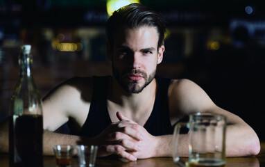 Man sitting alone in pub. Man with alcohol. Sad guy in bar. Guy in dark bar. Alcohol problem. Lonely man drinking whiskey at restaurant. Depressed man with glass of beer. Nightlife club.