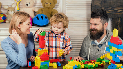 Family playing with colorful plastic building blocks at home. Happy family fun. Mother and father play with their son. Early childhood development, kids creativity. Family bonding. Family of 3.