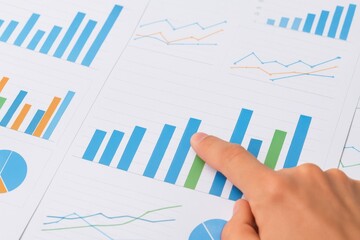 Detailed analysis of financial data shown in graphs and charts with a hand pointing at a blue bar representing growth in an office setting.
