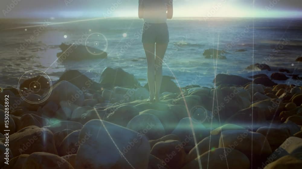 Poster camera pulling back showing woman on rocks jumping activating tech hud graphics pulsing over ocean