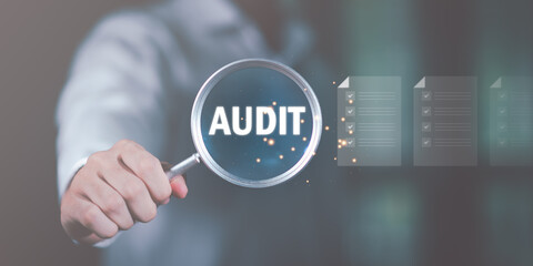 Businessman holding a magnifying glass, showing Audit Document concept,quality assessment...
