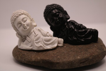 Black and White Reclining Buddha statues on a stone base