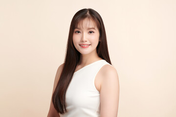 Fototapeta premium A beautiful young Asian woman with clean, fresh skin against a beige background. Skincare, facial treatment, cosmetology, beauty, and spa. An elegant portrait of an Asian woman.